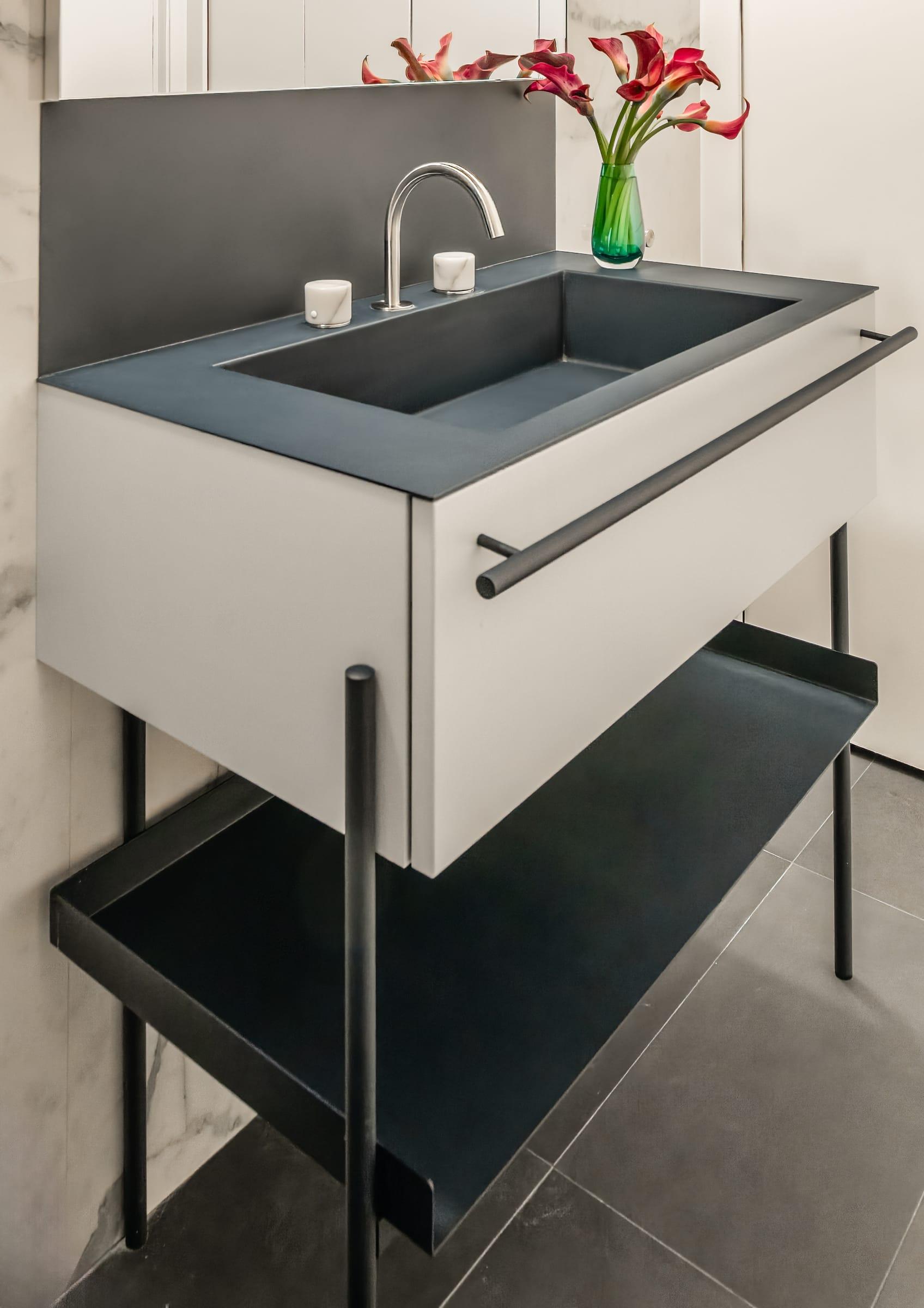 Grey washbasin on an open black steel stand with a towel rail