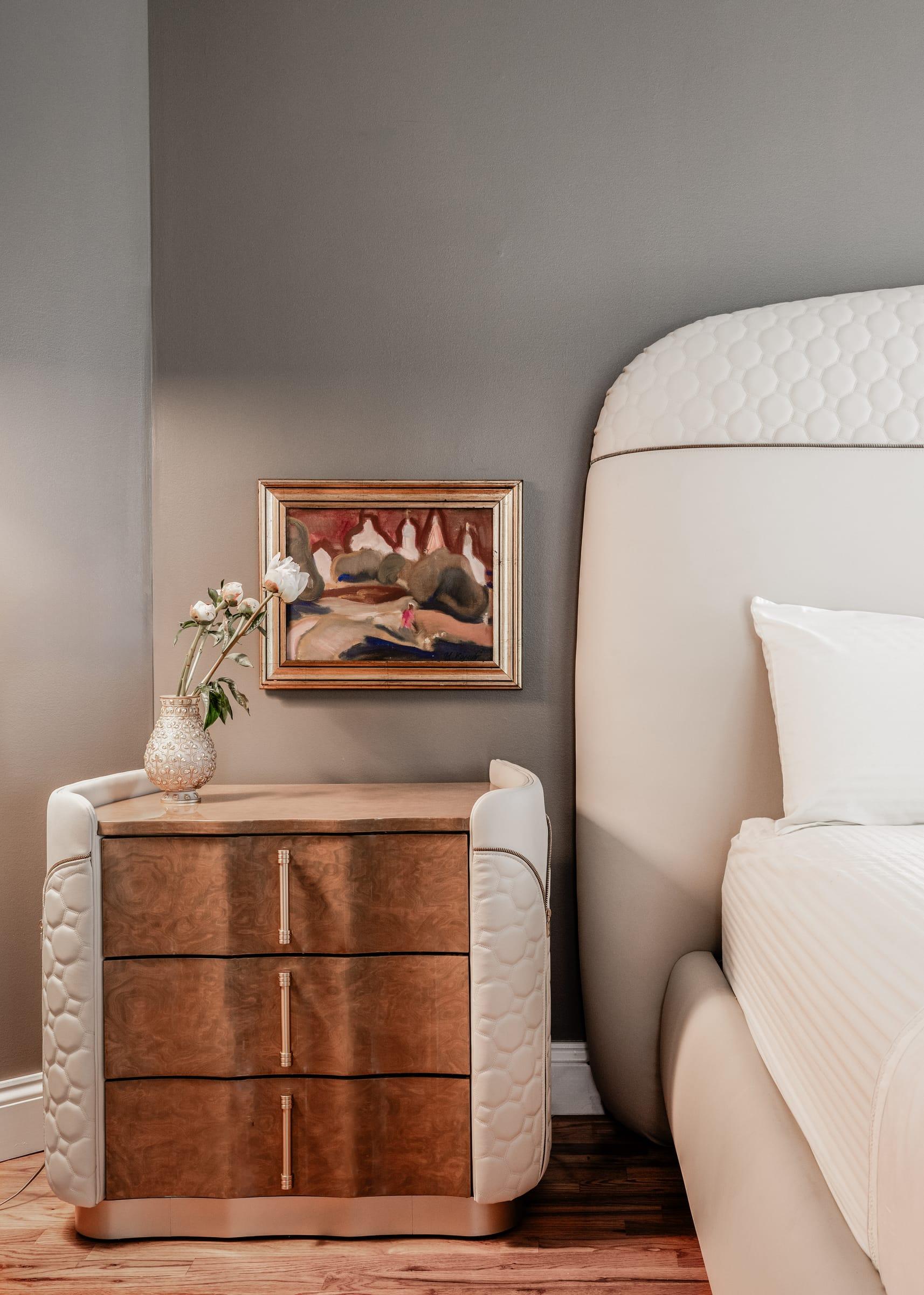 Walnut bedside chest beside an upholstered bed