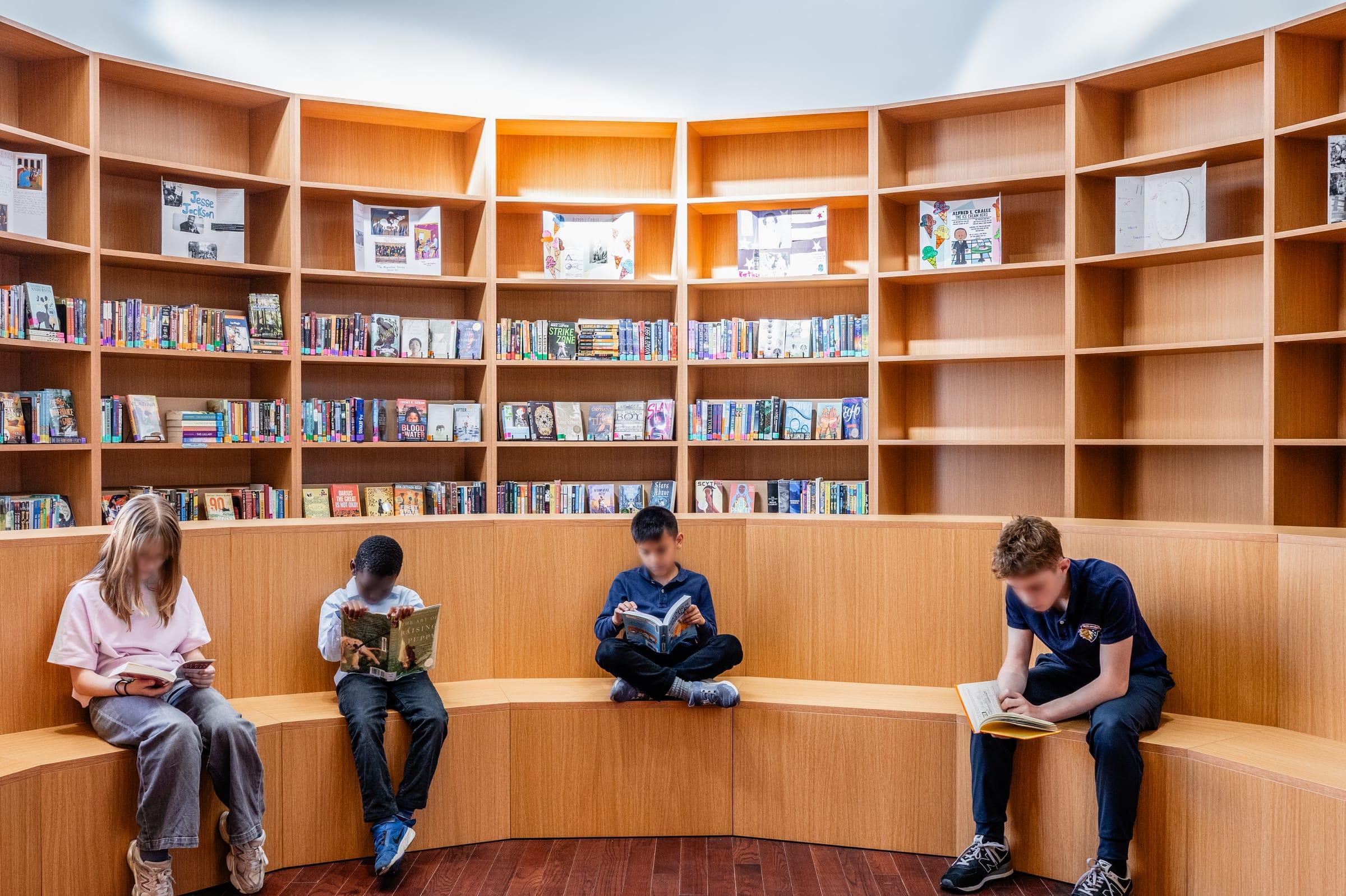 Students reading on a curved wood bench under the shelves