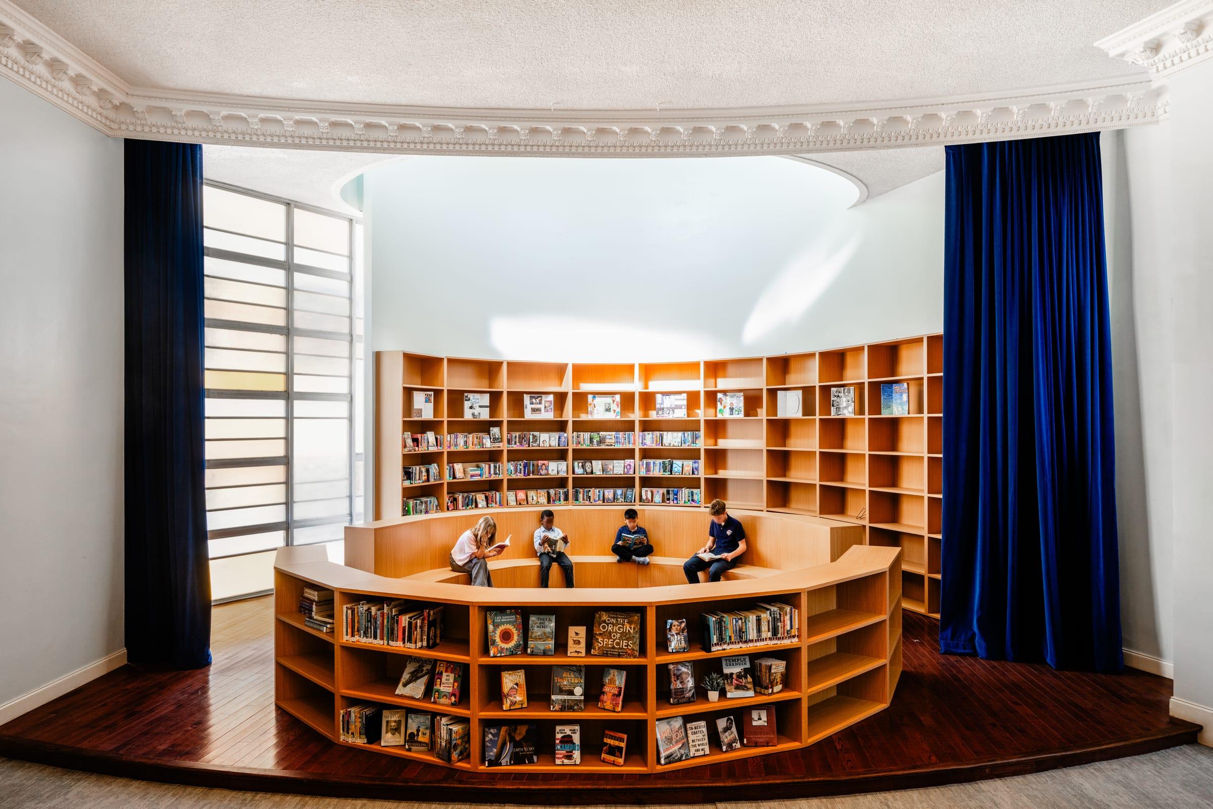 Round library of wood shelves behind a blue curtain