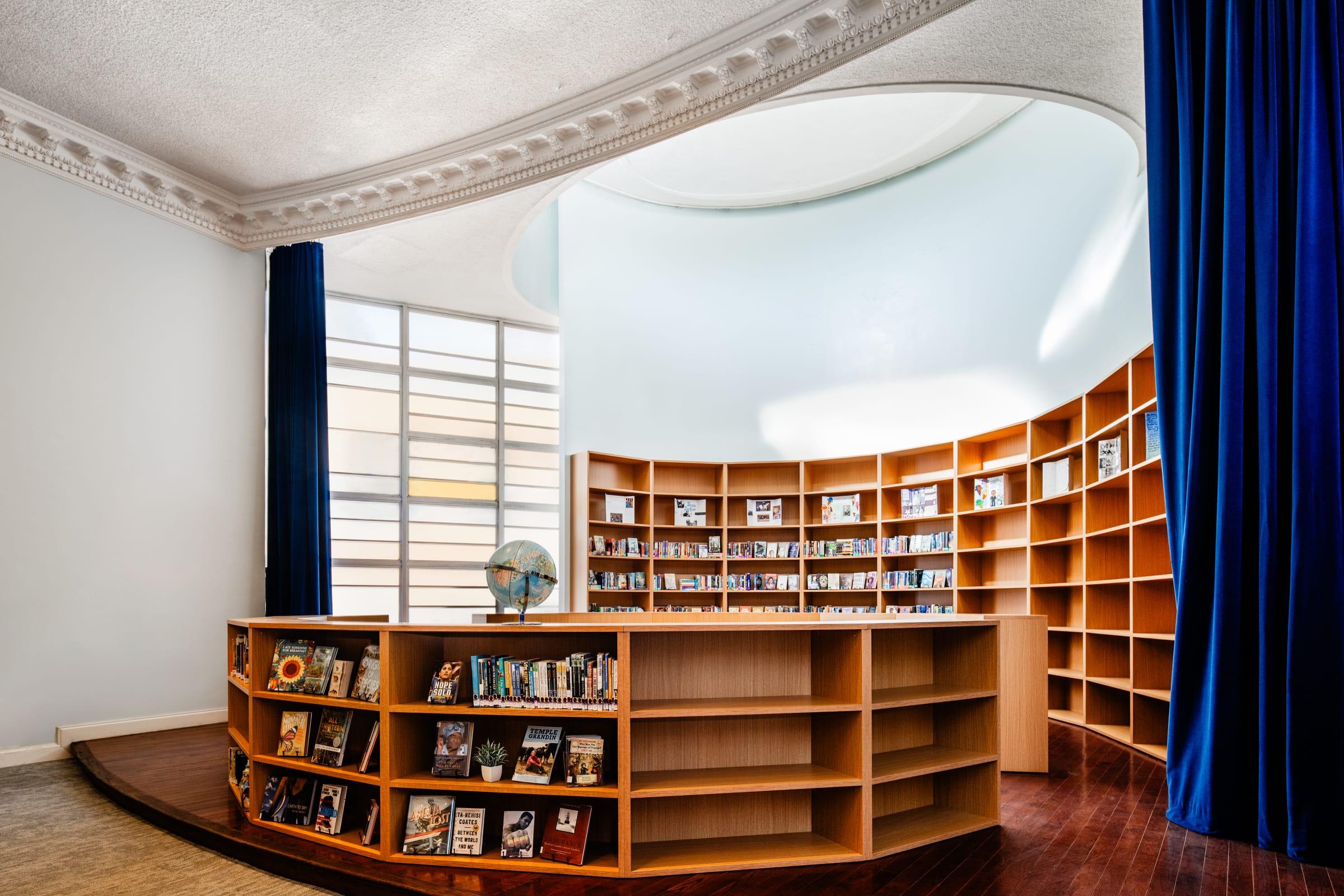 Curved library of wood shelves around a round room with a blue curtain