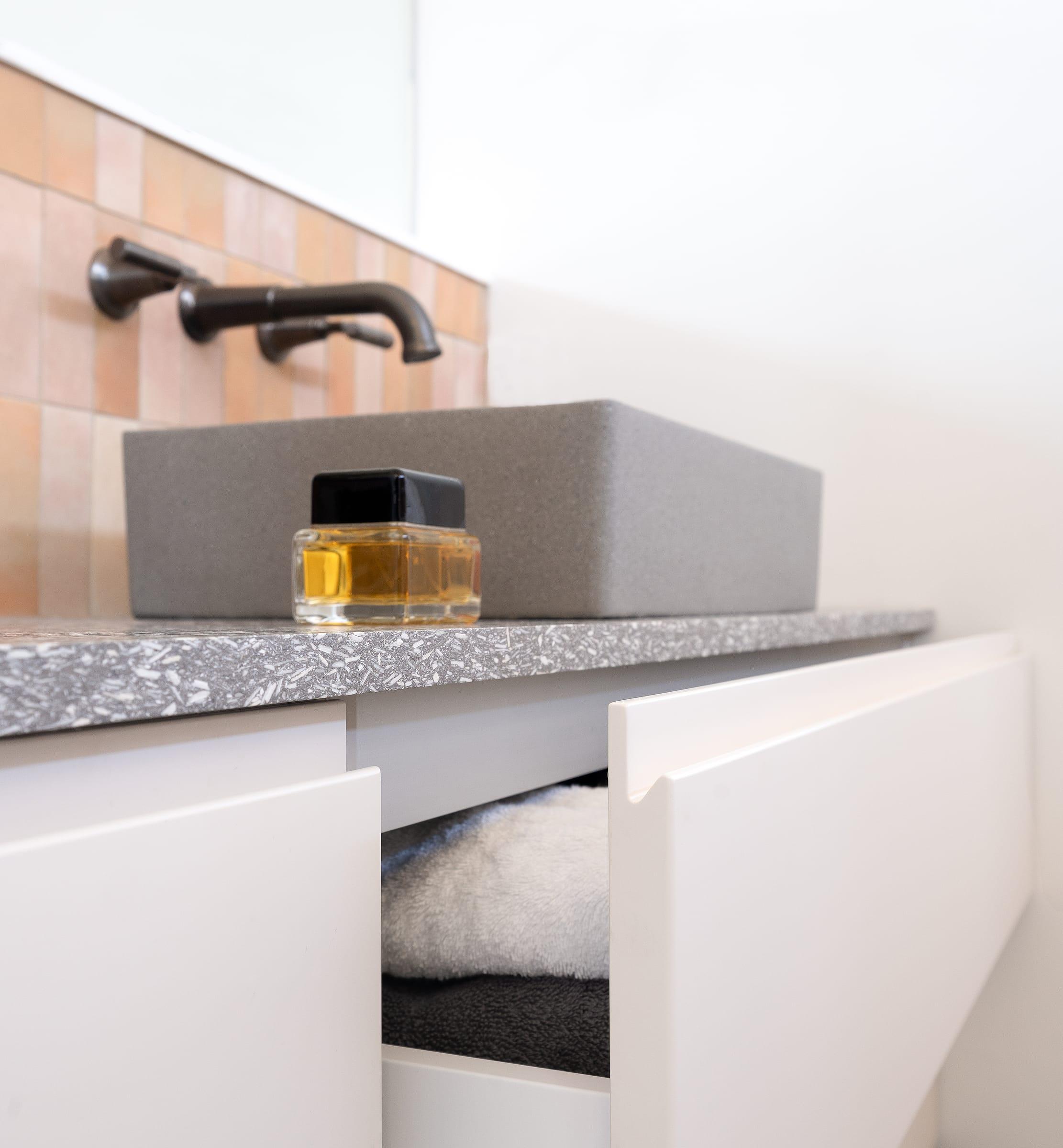 Open drawer under a grey stone basin