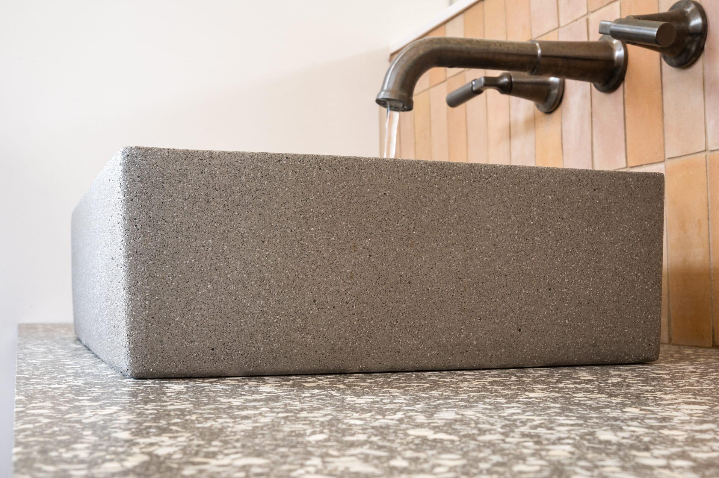 Grey stone basin with a bronze wall tap