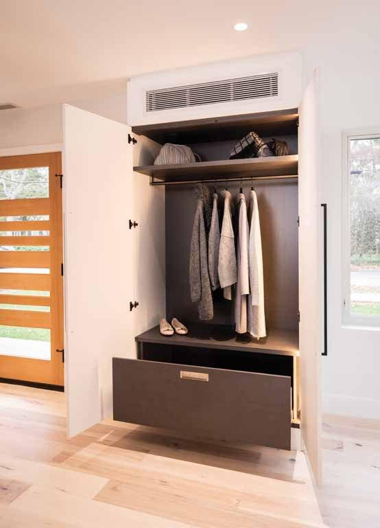White wardrobe open onto hanging jackets and a drawer, beside the front door