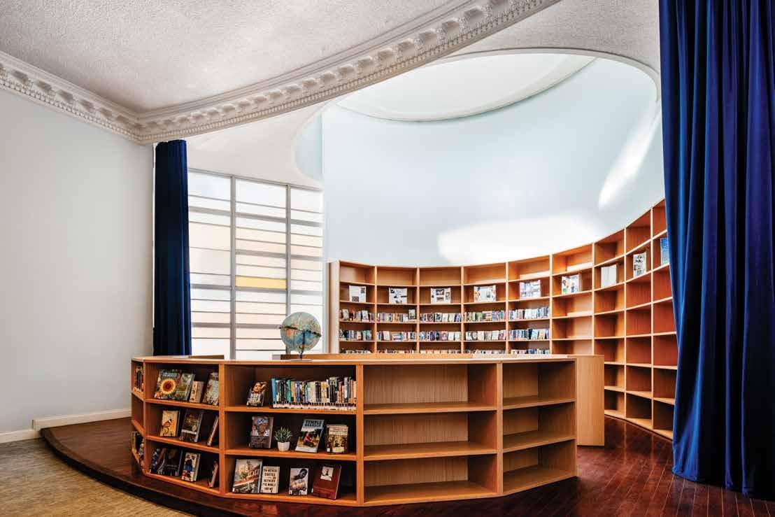 Curved library of wood shelves around a round room with a blue curtain
