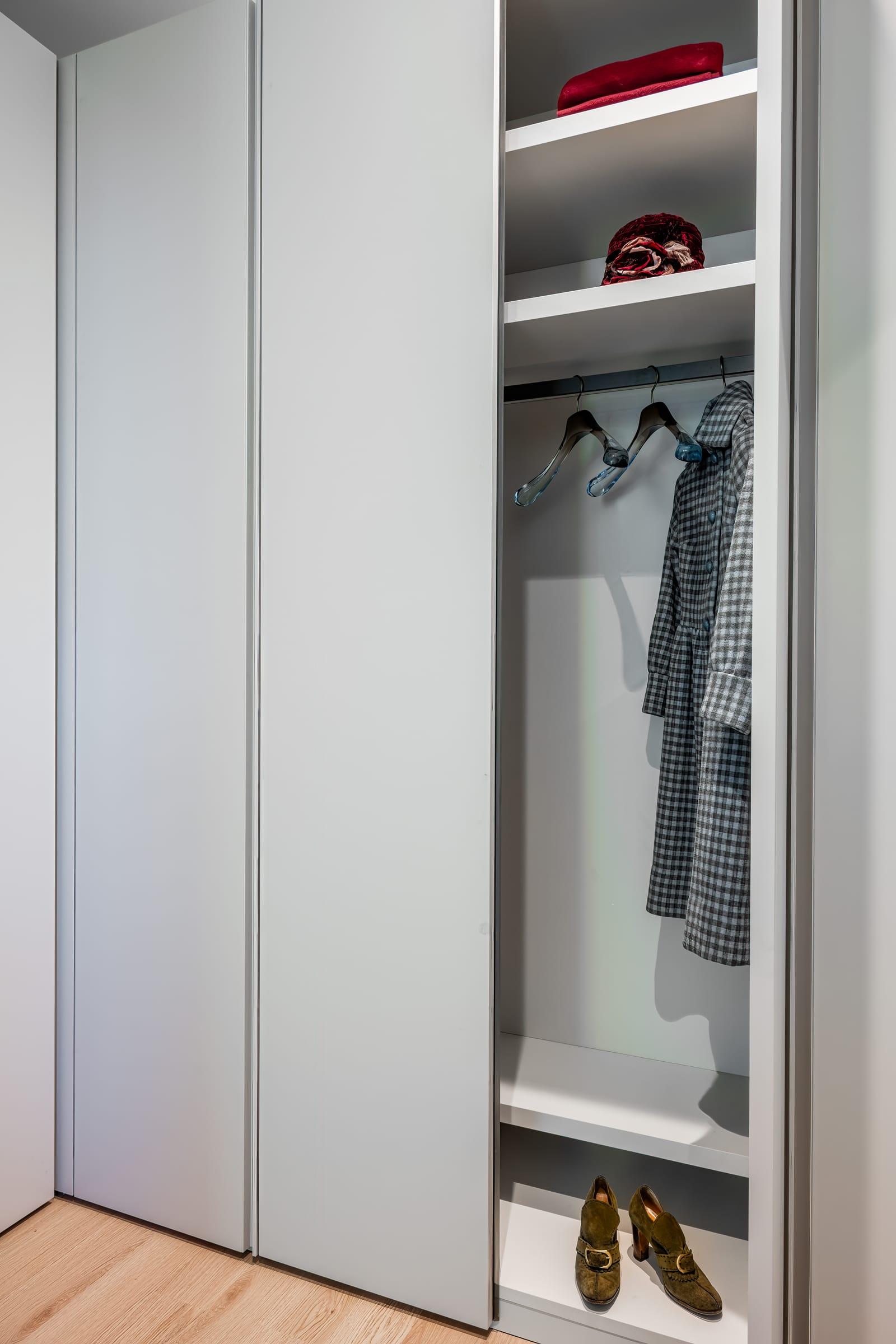 Grey wardrobe open onto shelves and hanging coats