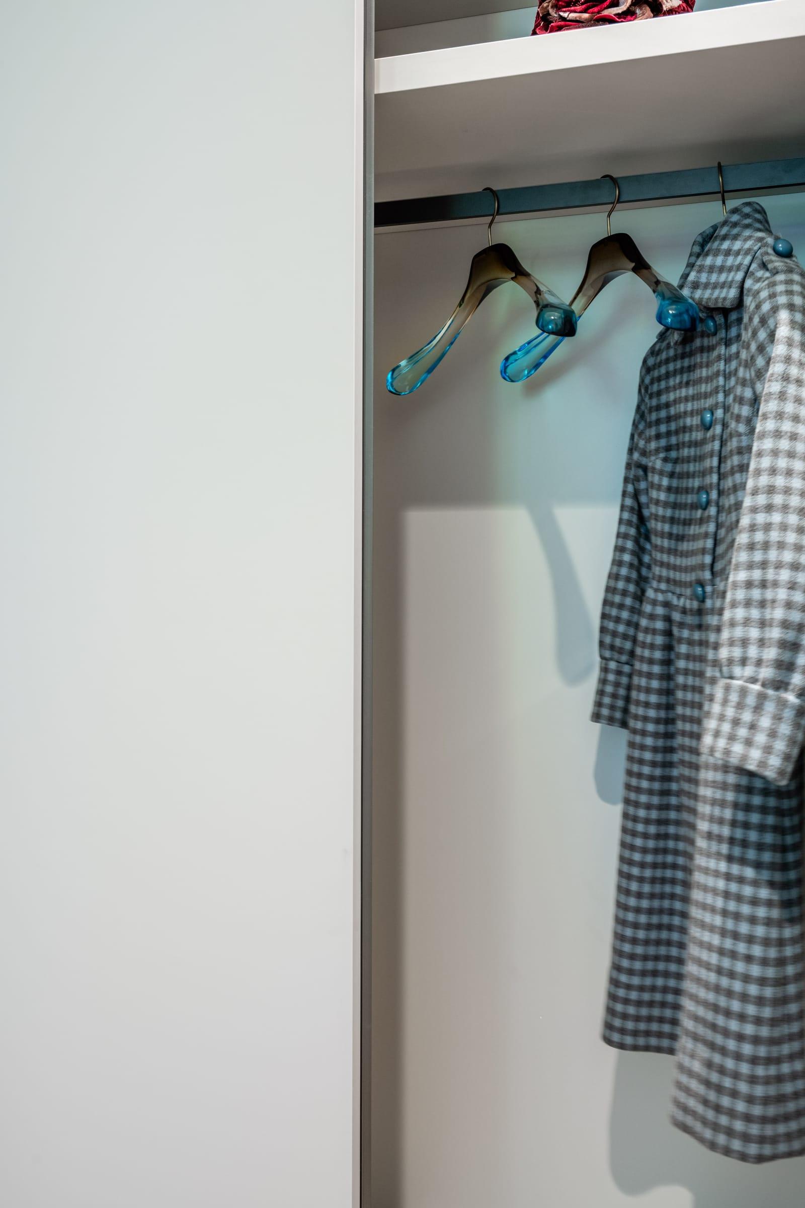 Hanging coats on blue hangers inside a grey wardrobe