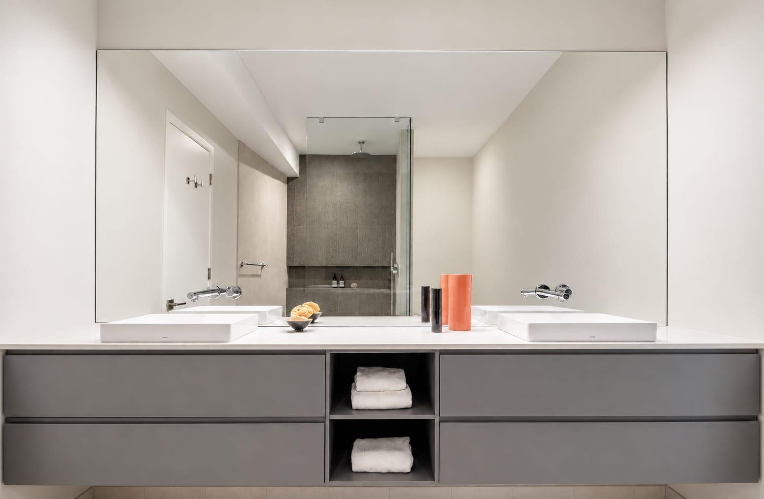 Grey double vanity with open shelves under a wide mirror