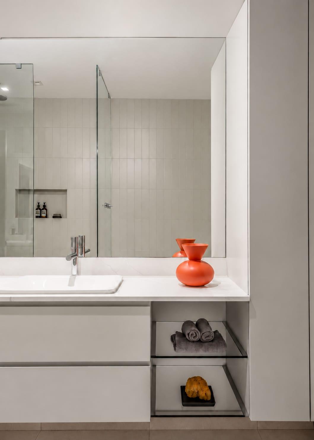 White vanity with open shelves beside a glass shower