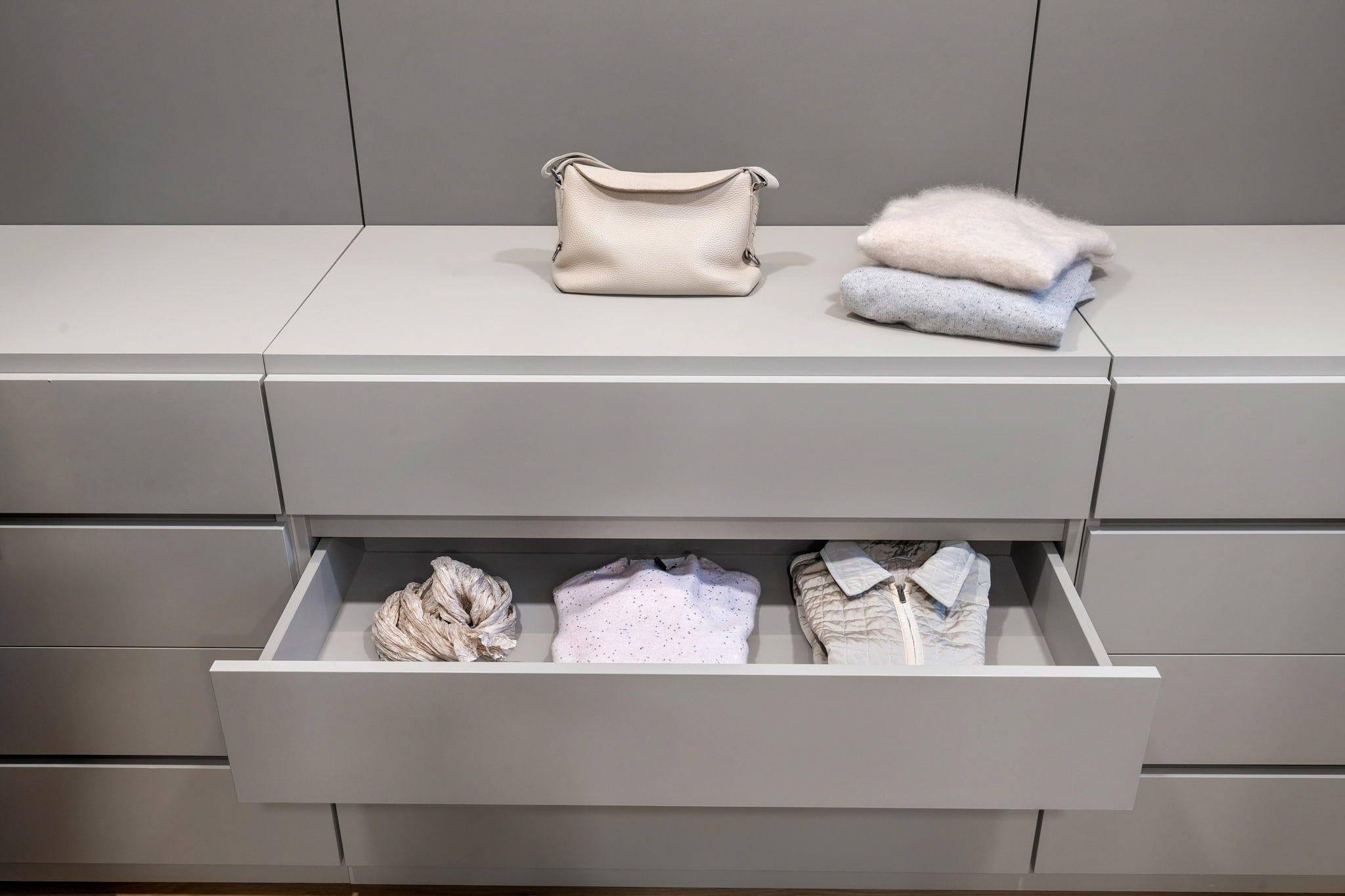 Open grey drawer holding folded clothes