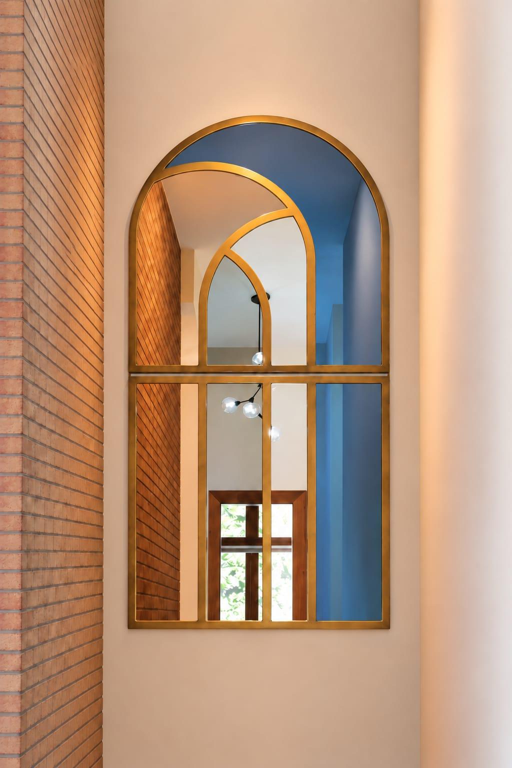 Arched brass mirror in a niche beside a brick wall
