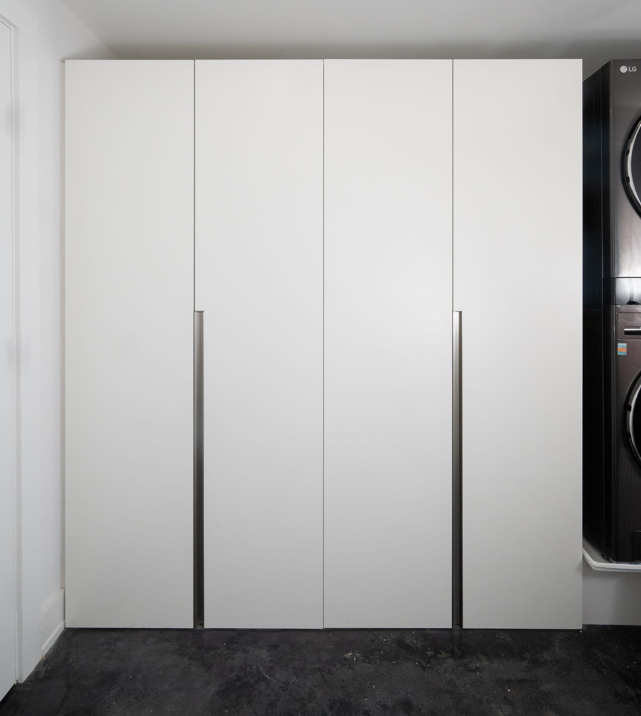 White wardrobe with tall doors beside a washing machine