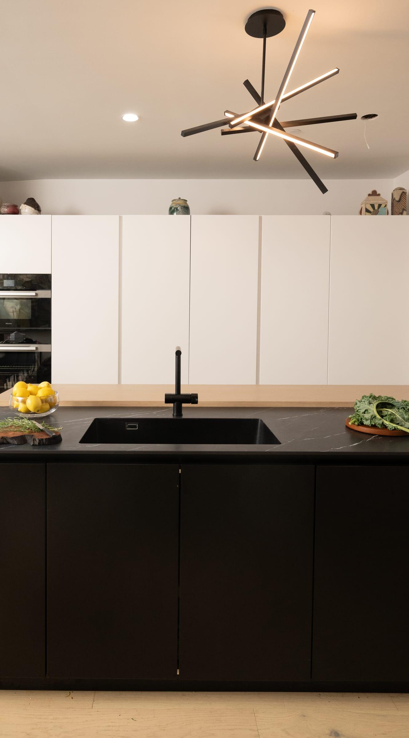 Black lower cabinets and white wall units under a starburst pendant