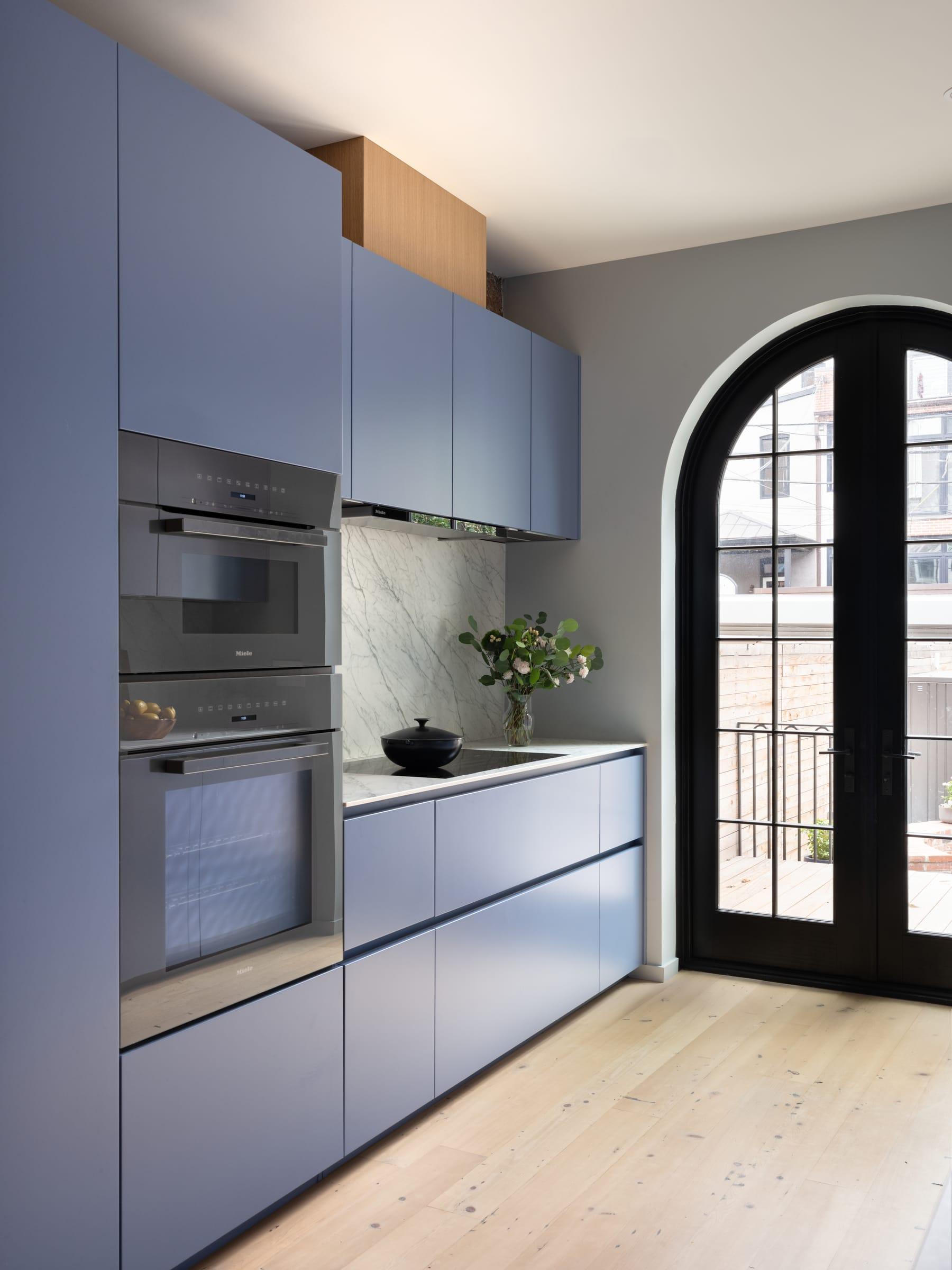 Blue tall units with ovens beside an arched glazed door
