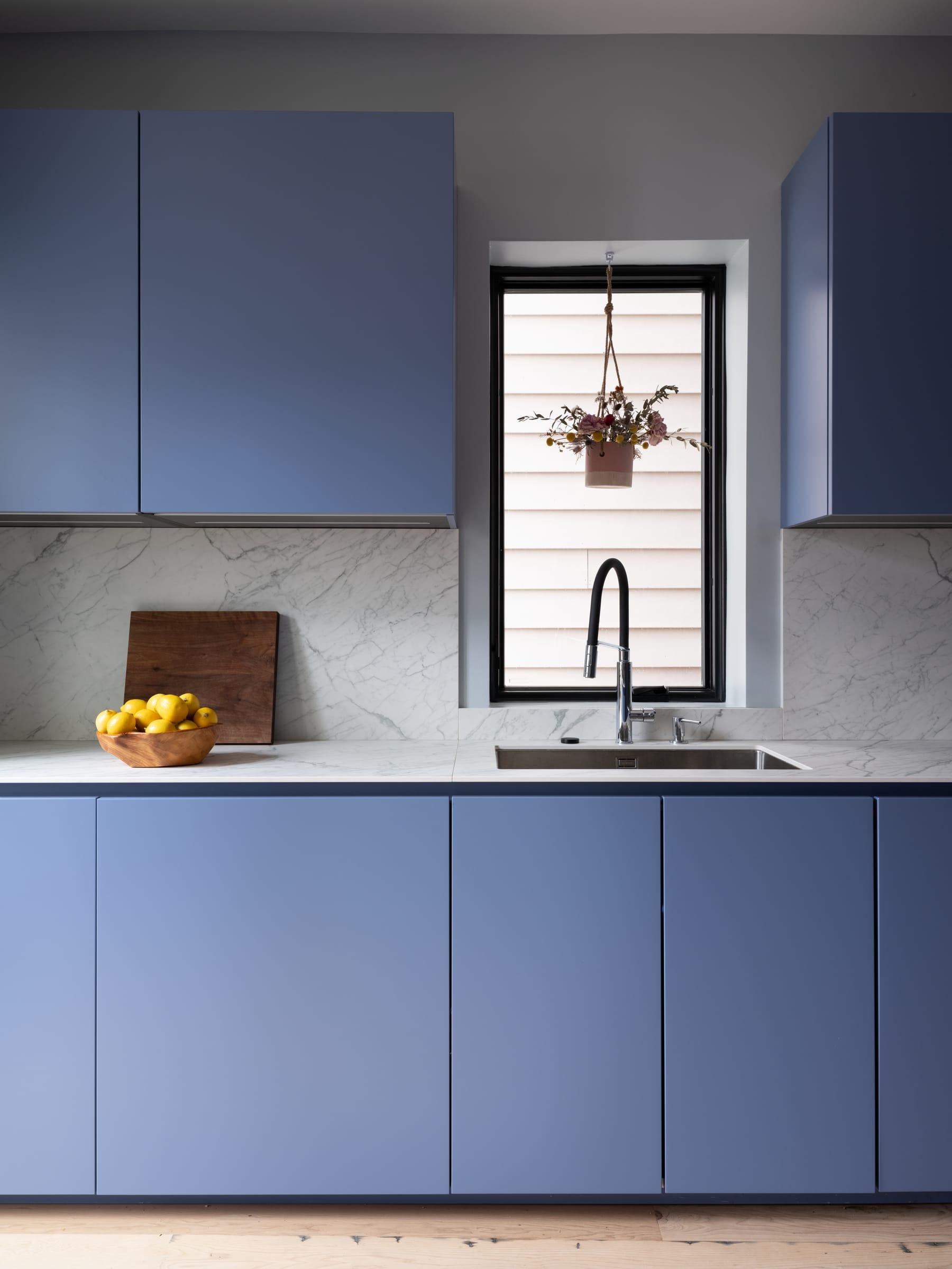 Blue cabinets around a window over the sink
