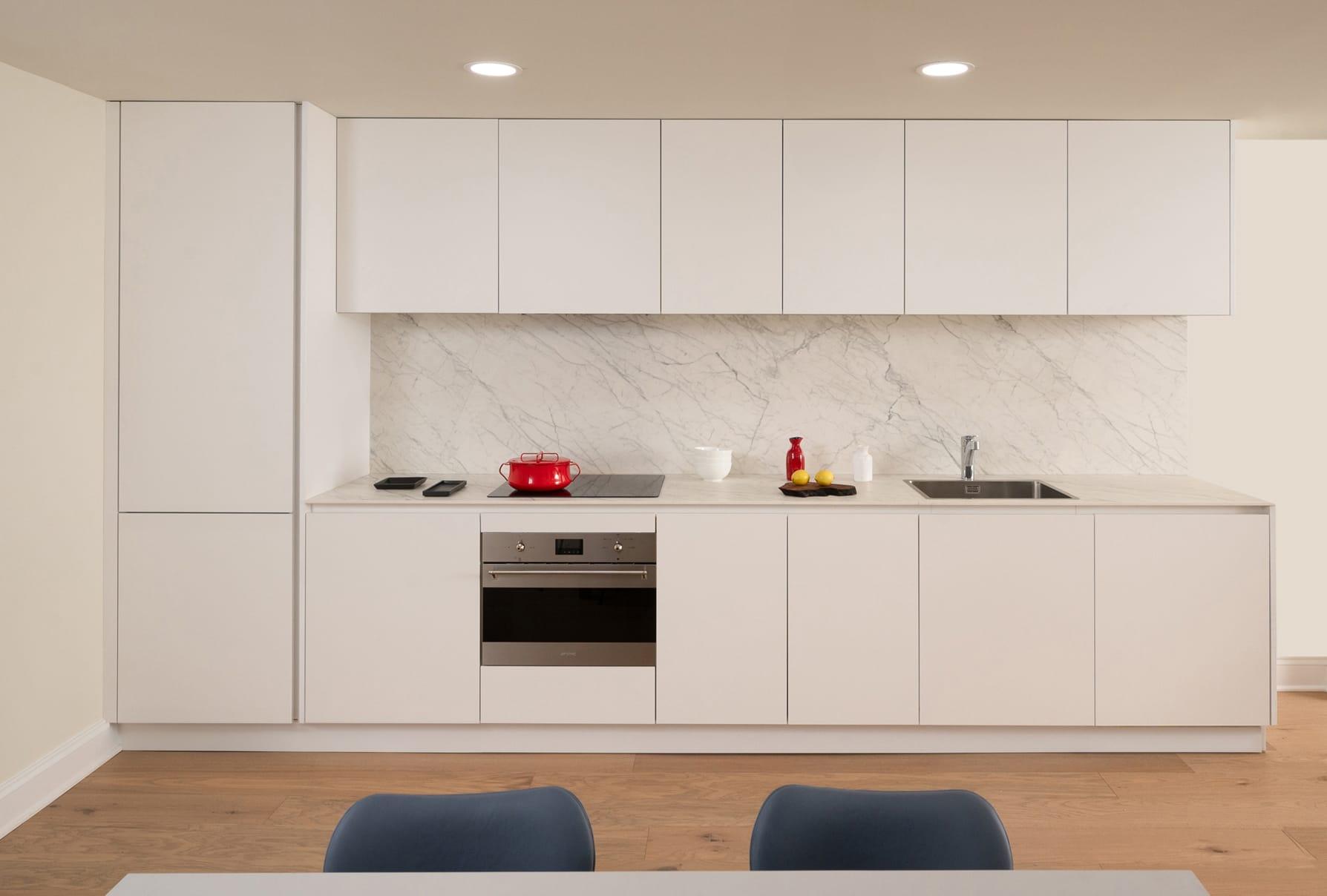White kitchen with tall units and a marble splashback