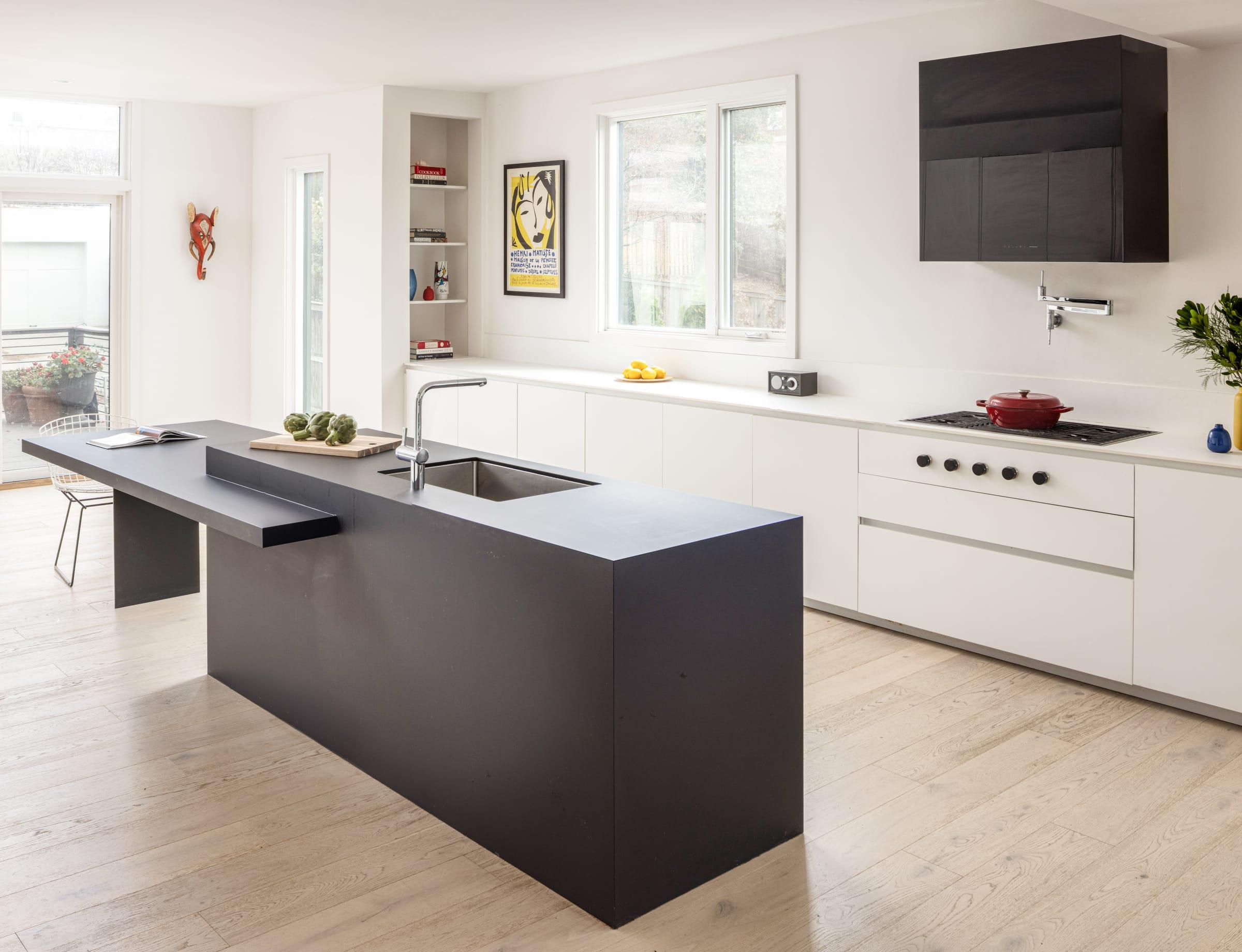 White kitchen with a dark grey island and a black hood on the wall