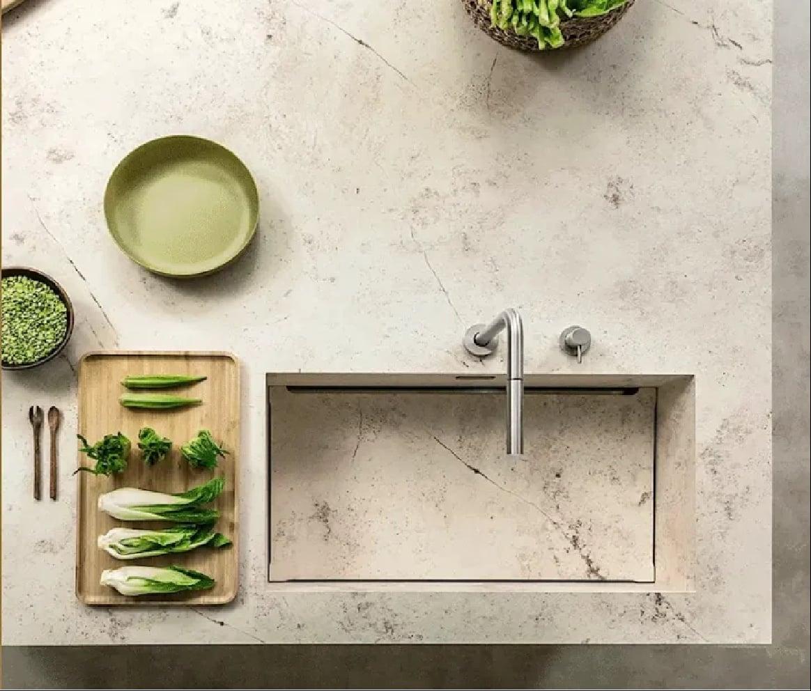 Stone counter from above with an integrated sink, bowls and a board of greens