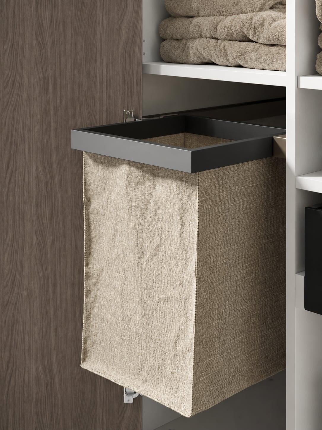 Pull-out linen laundry basket in a wardrobe beside shelves of towels