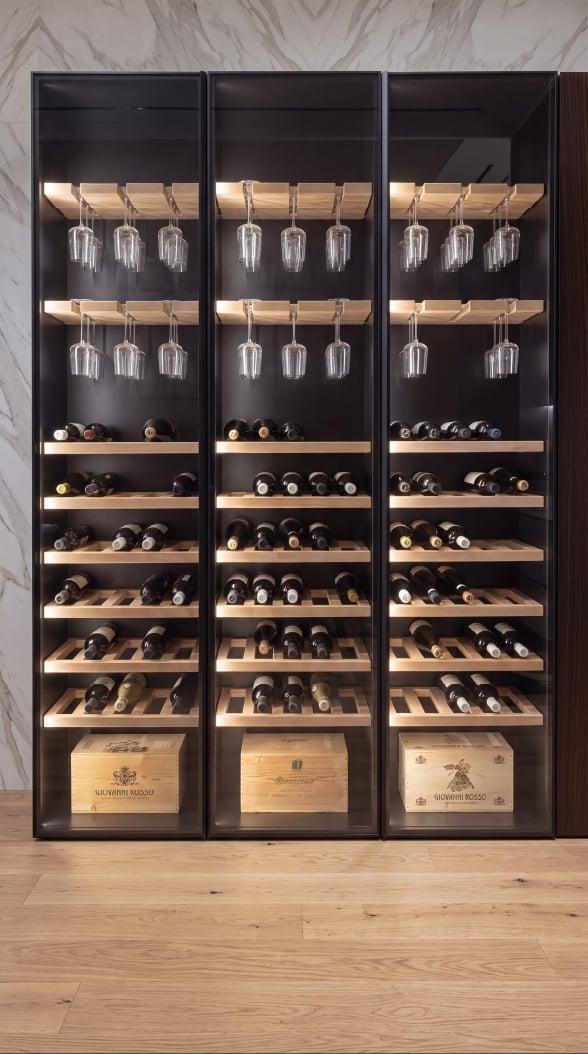 Glass-fronted wine cabinet in dark wood with lit shelves for bottles and glasses