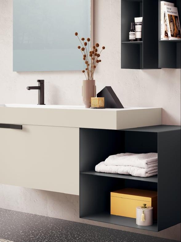 Beige floating vanity with a black tap, open shelves with towels and dark wall cabinets