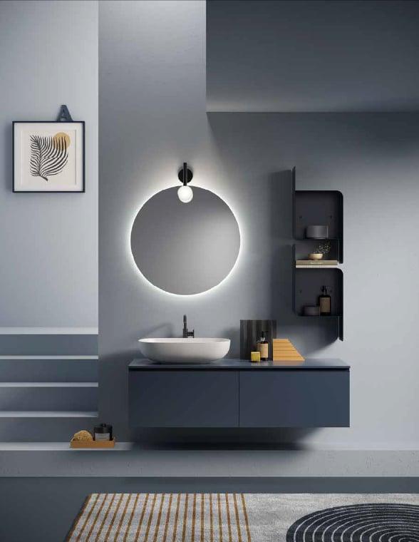 Grey-blue bathroom with a navy floating vanity, a white basin and a round backlit mirror