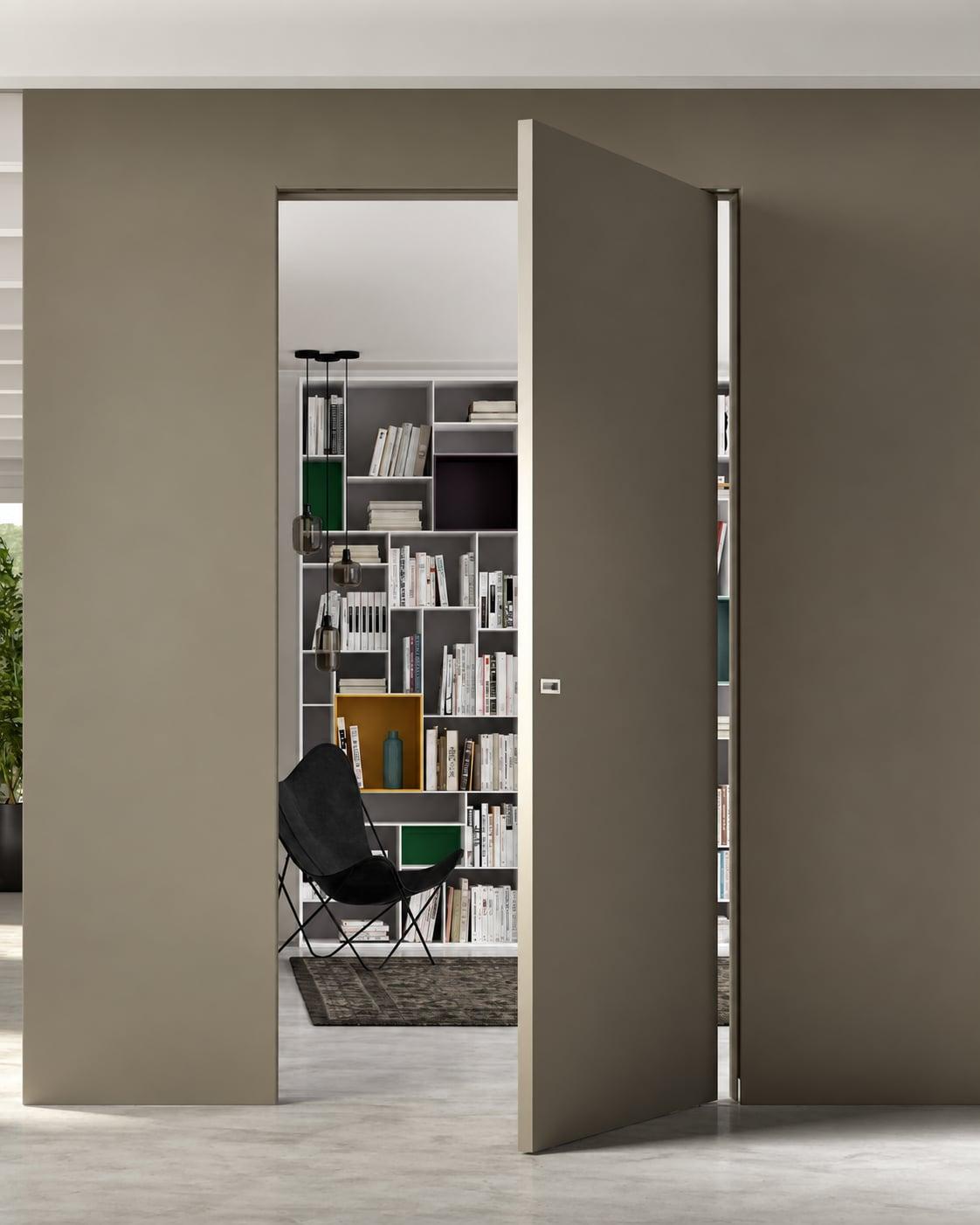 Taupe pivot door open onto a study with a bookcase