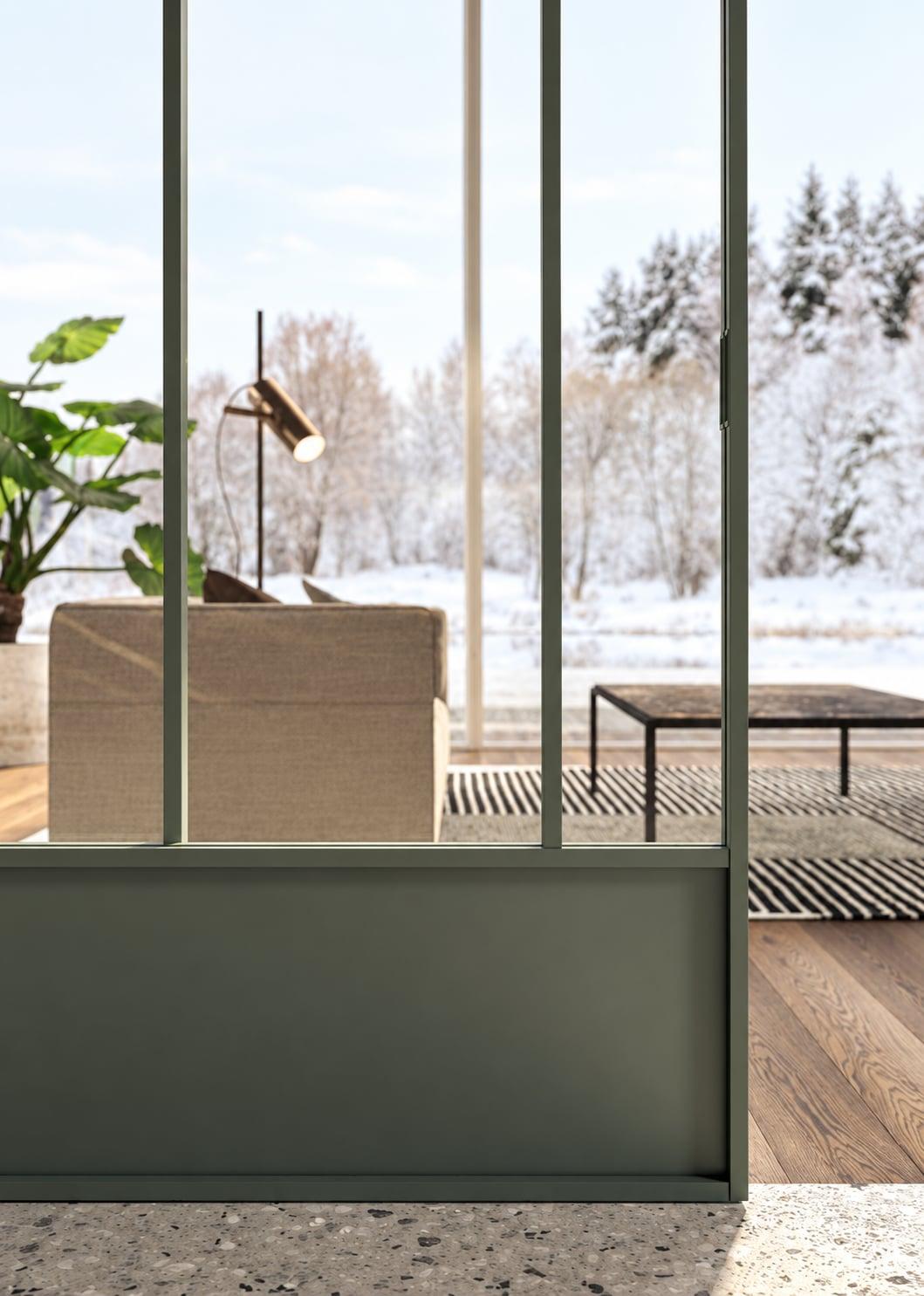 Green-framed glass partition looking onto a snowy garden