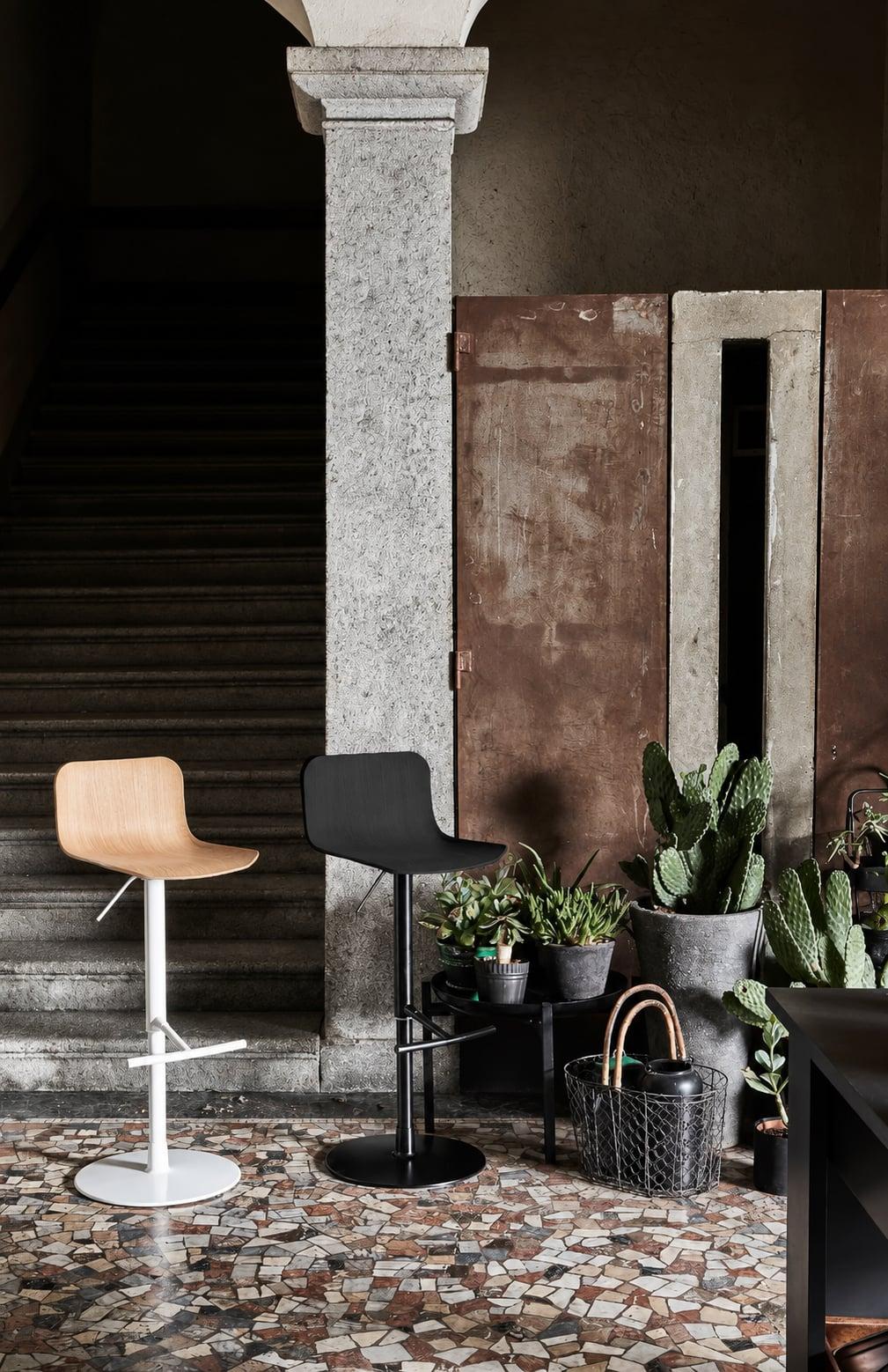 Two swivel bar stools in a courtyard with a stone column and cacti