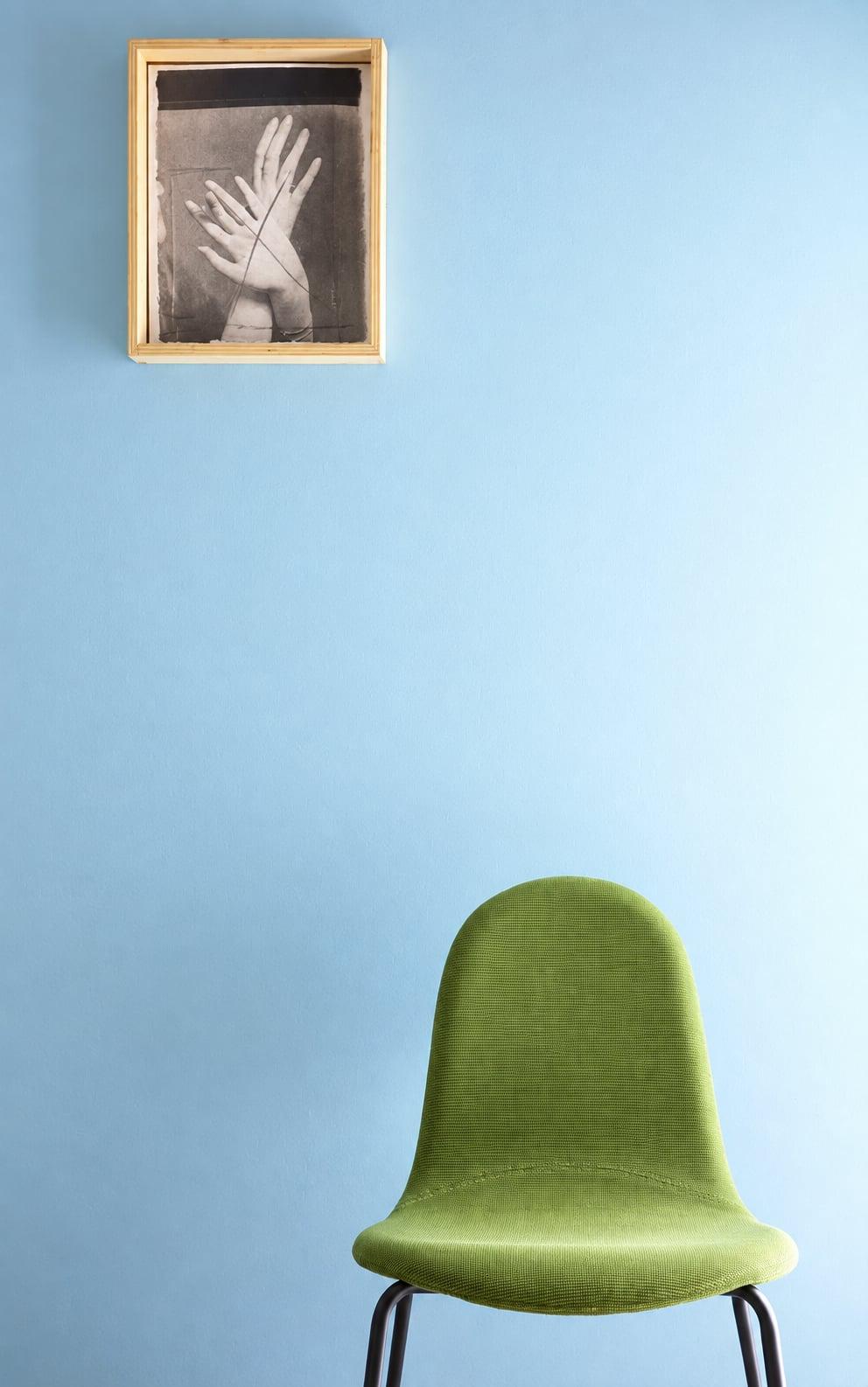 Green upholstered chair against a pale blue wall