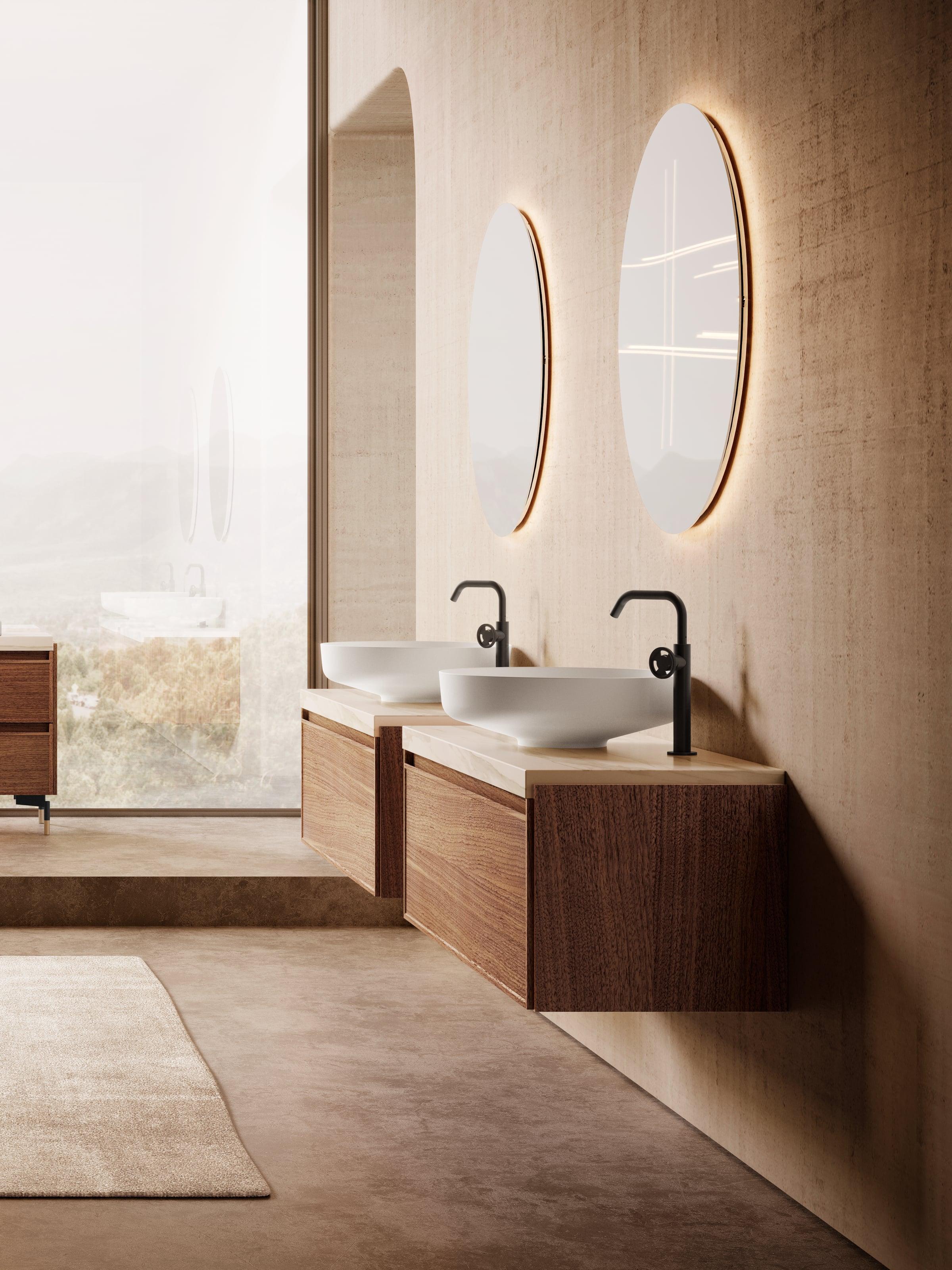 Floating walnut double vanity with two white basins, black taps and round backlit mirrors on a plaster wall