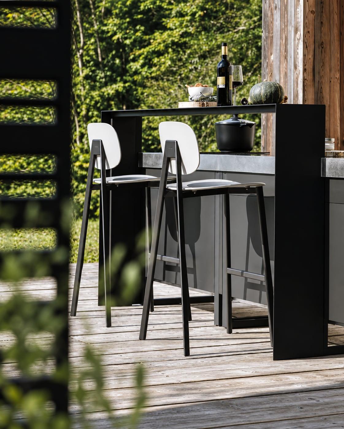 Black outdoor bar table and stools on a wooden deck
