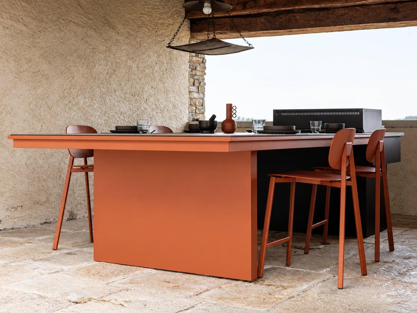 Terracotta outdoor kitchen island with bar stools under a stone pergola