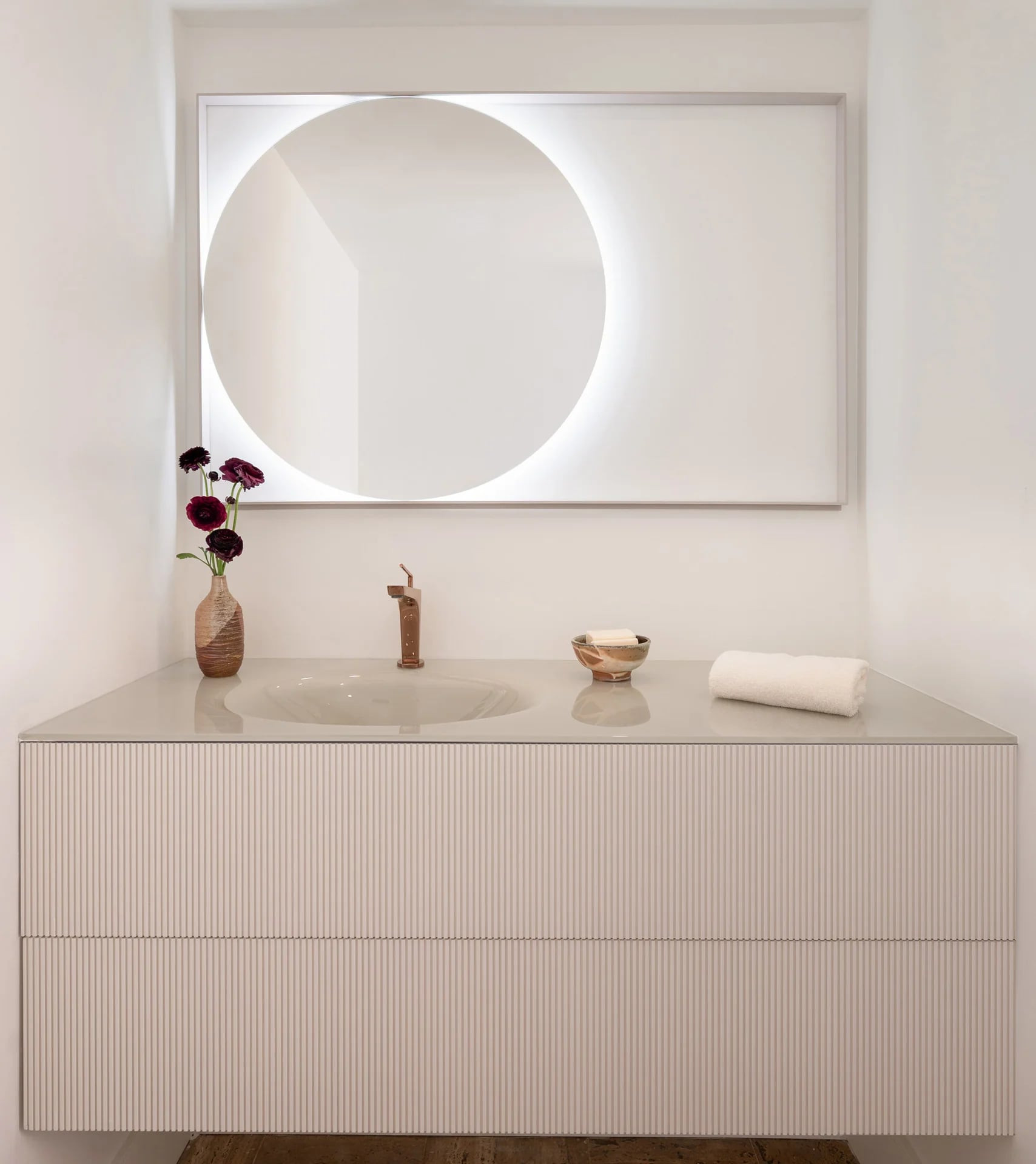 Reeded vanity with an integrated basin and a round backlit mirror